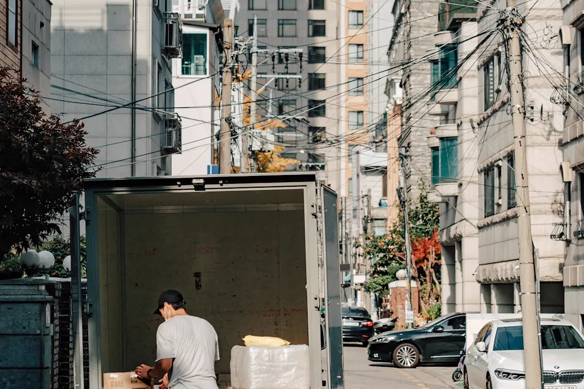 Conductor descargando cajas de mercancía de un camión de reparto en una calle de la ciudad