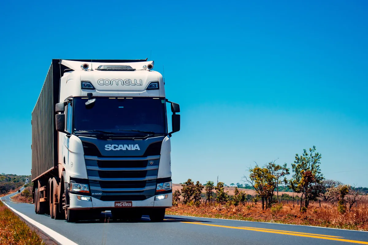 Camión articulado transportando un remolque con contenedor completo por una autopista abierta